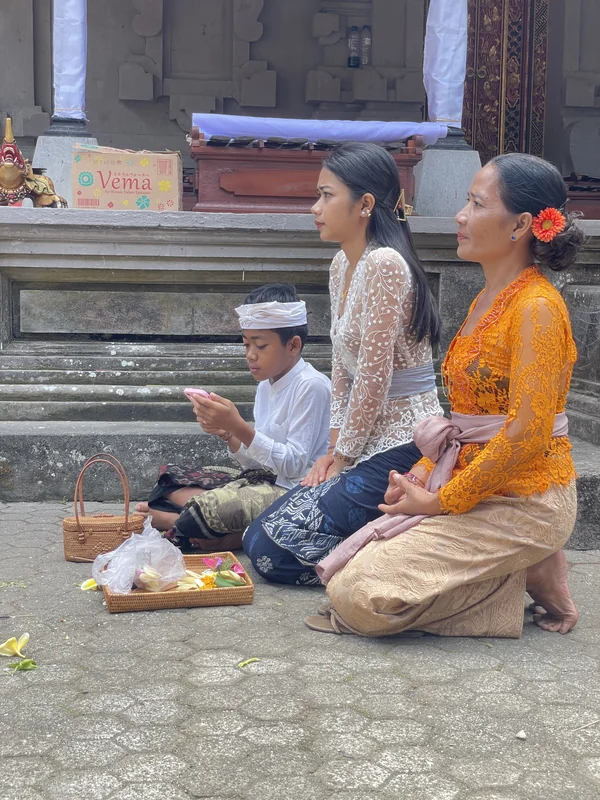 Familia balinesa con ropa tradicional kebaya rezando durante una ceremonia hindú en un templo de Bali