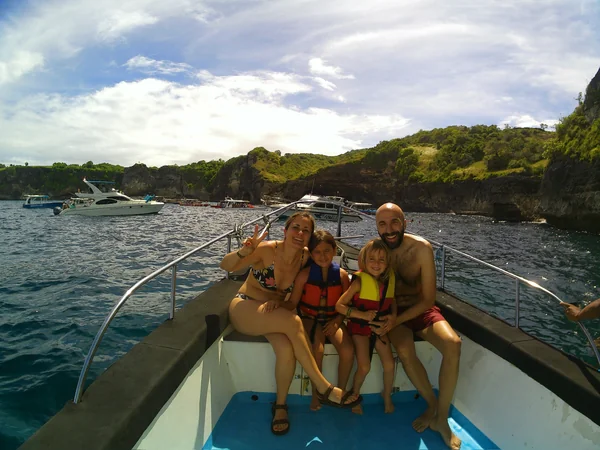 Familia con dos niñas en barco con chalecos salvavidas listos para hacer snorkel en Nusa Penida, tour familiar Bali