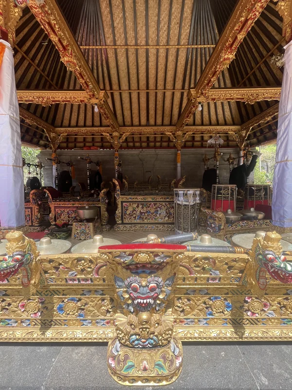 Pabellón balinés con instrumentos tradicionales de gamelán dorados y estatua de Barong en primer plano