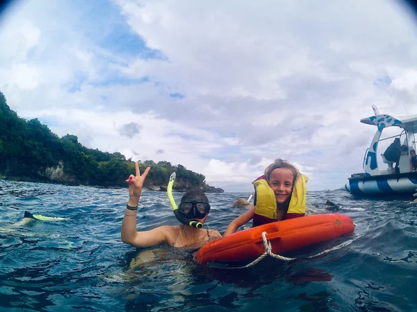 Madre e hija haciendo snorkel juntas en aguas tropicales cristalinas de Nusa Penida, experiencia familiar en Bali