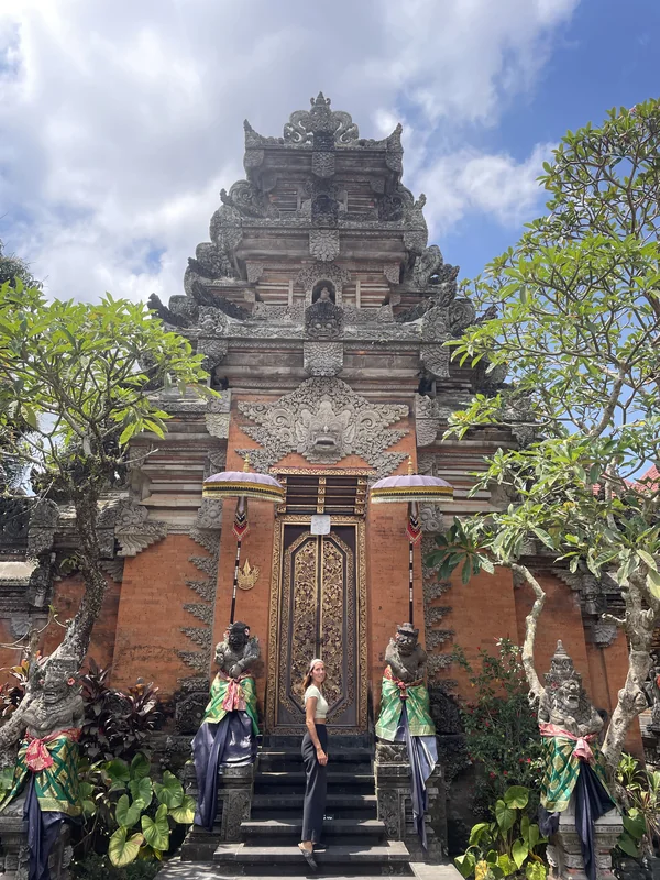 Viajera frente a la imponente fachada del Palacio Real de Ubud (Puri Saren Agung) con guardianes balineses