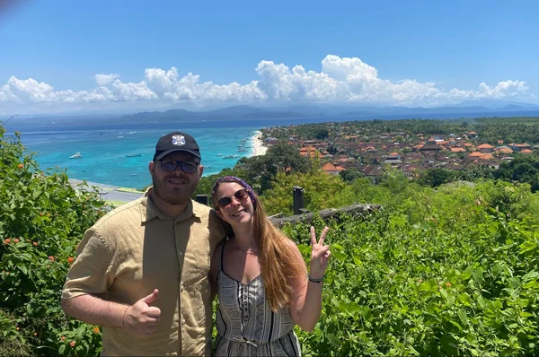 Pareja sonriendo en el mirador de Panorama Point con la bahía turquesa de Nusa Lembongan y Nusa Penida al fondo