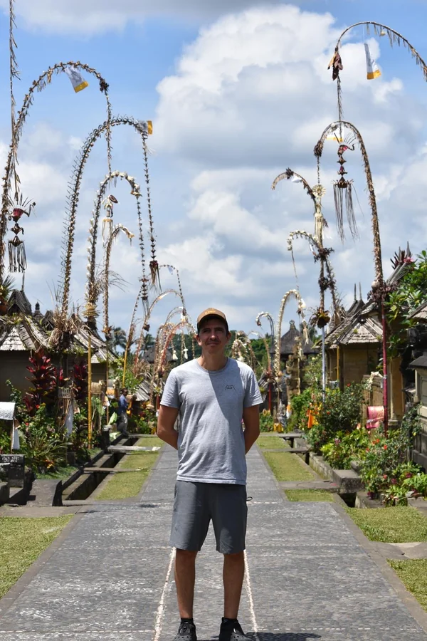 Hombre posando entre los altos penjor de bambú decorados durante la fiesta de Galungan en la aldea tradicional de Penglipuran