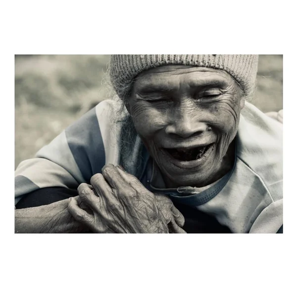 Retrato cercano en blanco y negro de una anciana de Flores sonriendo con manos curtidas por años de trabajo