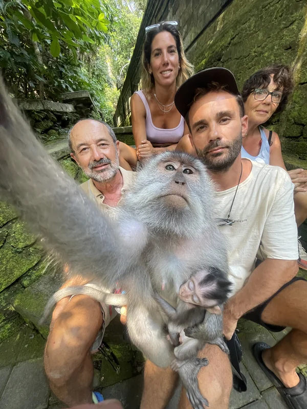 Grupo de viajeros haciéndose un selfie con un macaco en el Sacred Monkey Forest de Ubud, Bali