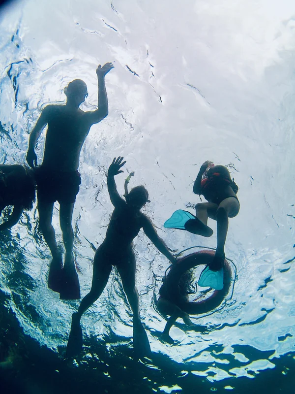 Siluetas de snorkelistas vistas desde abajo del agua a contraluz durante un tour de snorkel en Nusa Penida, Bali