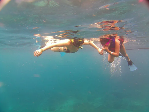 Dos viajeras adultas explorando los arrecifes de coral con aletas y gafas durante el tour de snorkel en Nusa Penida, Bali