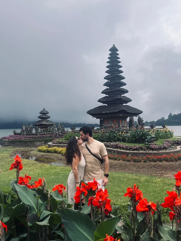 Pareja besándose frente a la pagoda de once techos del templo Ulun Danu Beratan sobre el lago Bratan en Bedugul