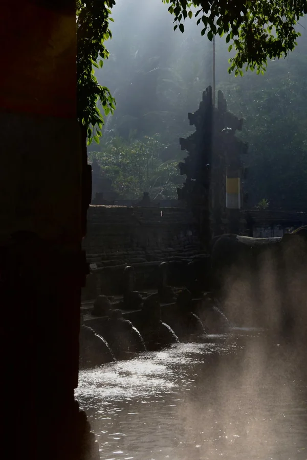 Fuentes rituales de purificación del templo Tirta Empul envueltas en una bruma mística al amanecer