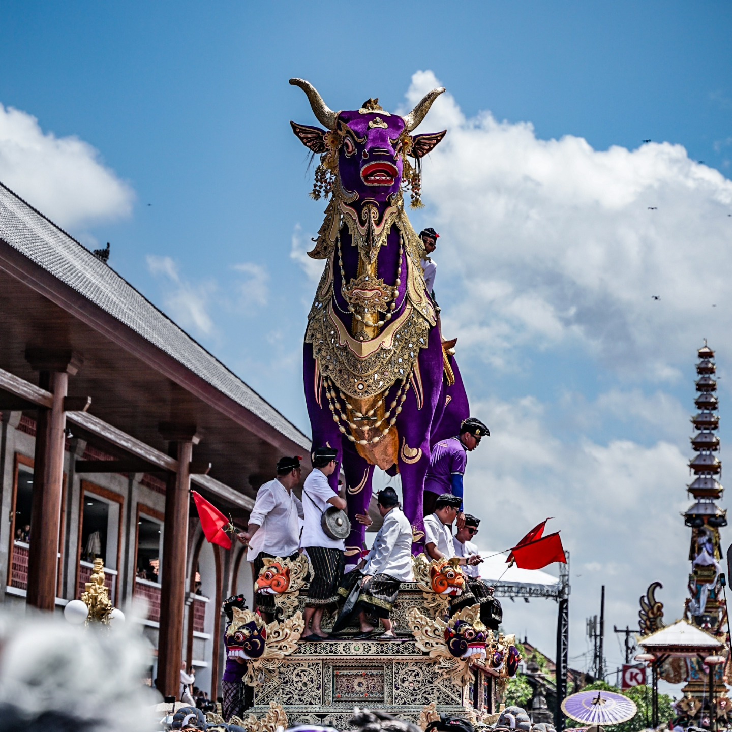 Torre bade de bambú y papel cargada en procesión durante un ngaben balinés, con familias en sarong blanco