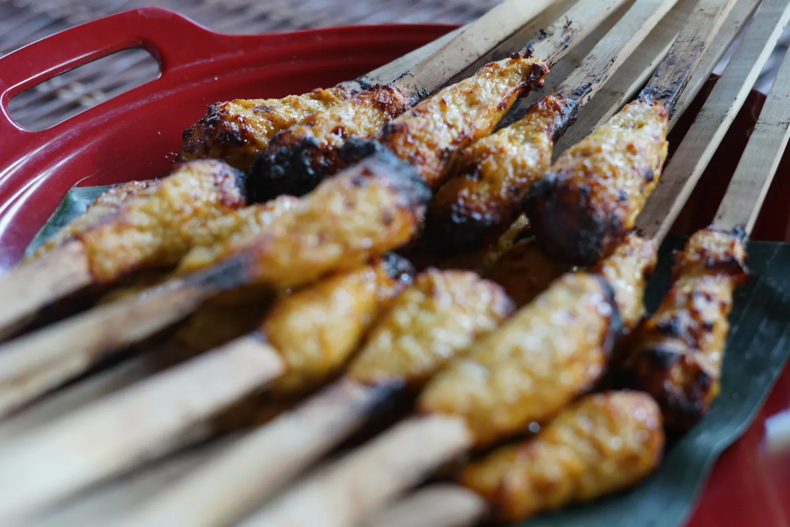 Brochetas de sate lilit balinés recién hechas en un plato sobre hoja de banana