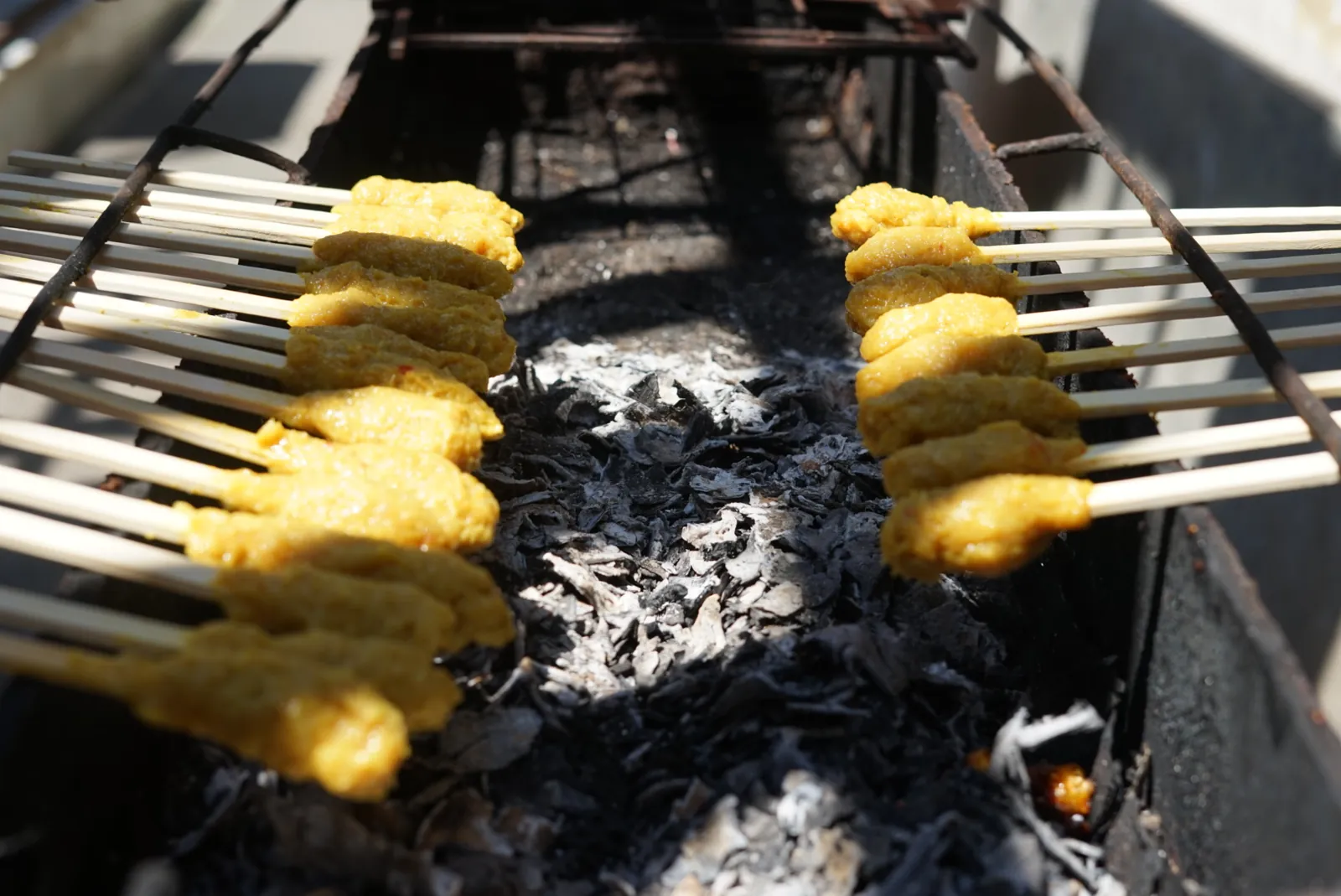 Brochetas de sate balinés asándose sobre la parrilla de carbón