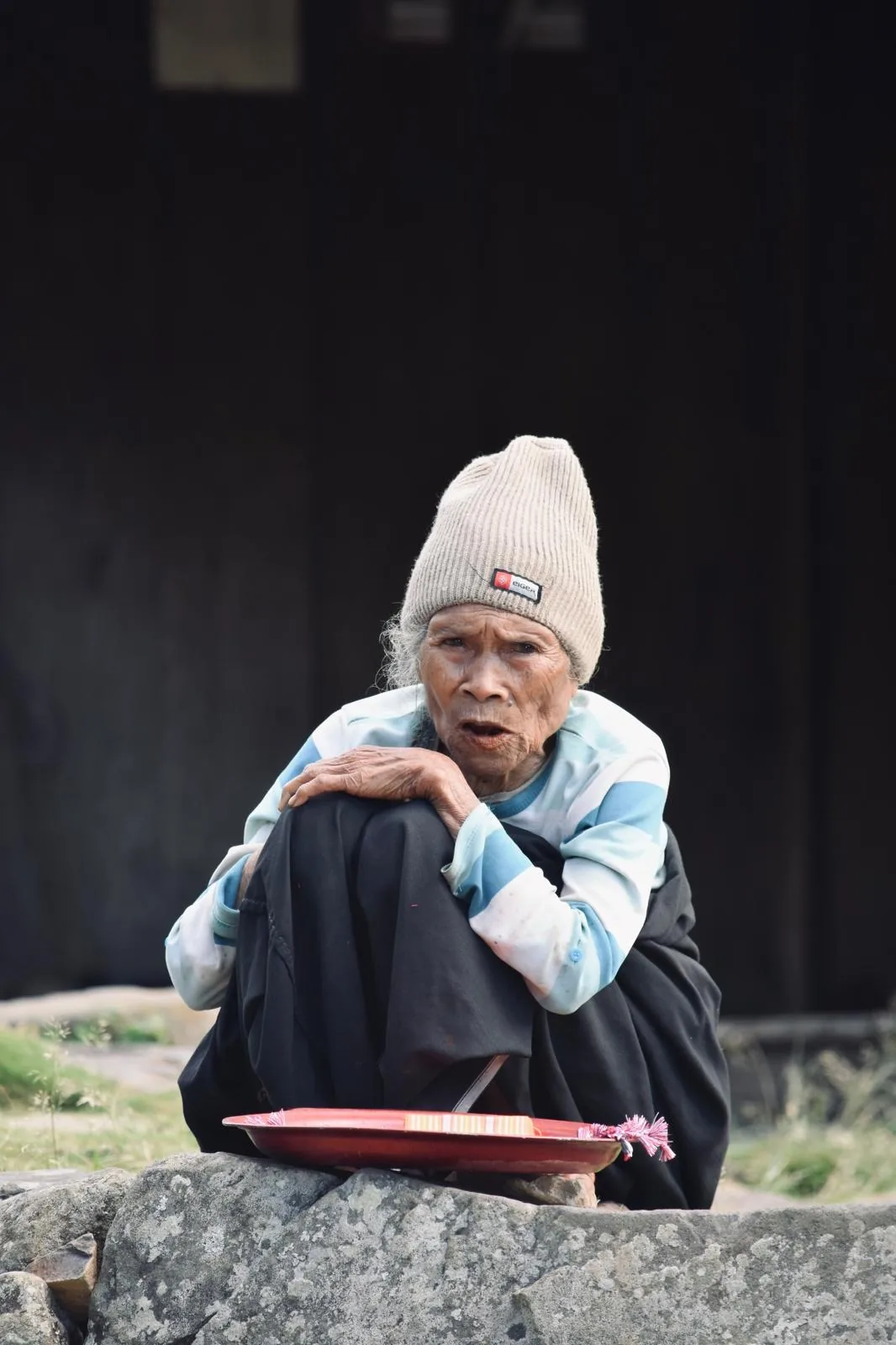 Anciana manggarai sentada frente a su mbaru niang en Wae Rebo, Flores