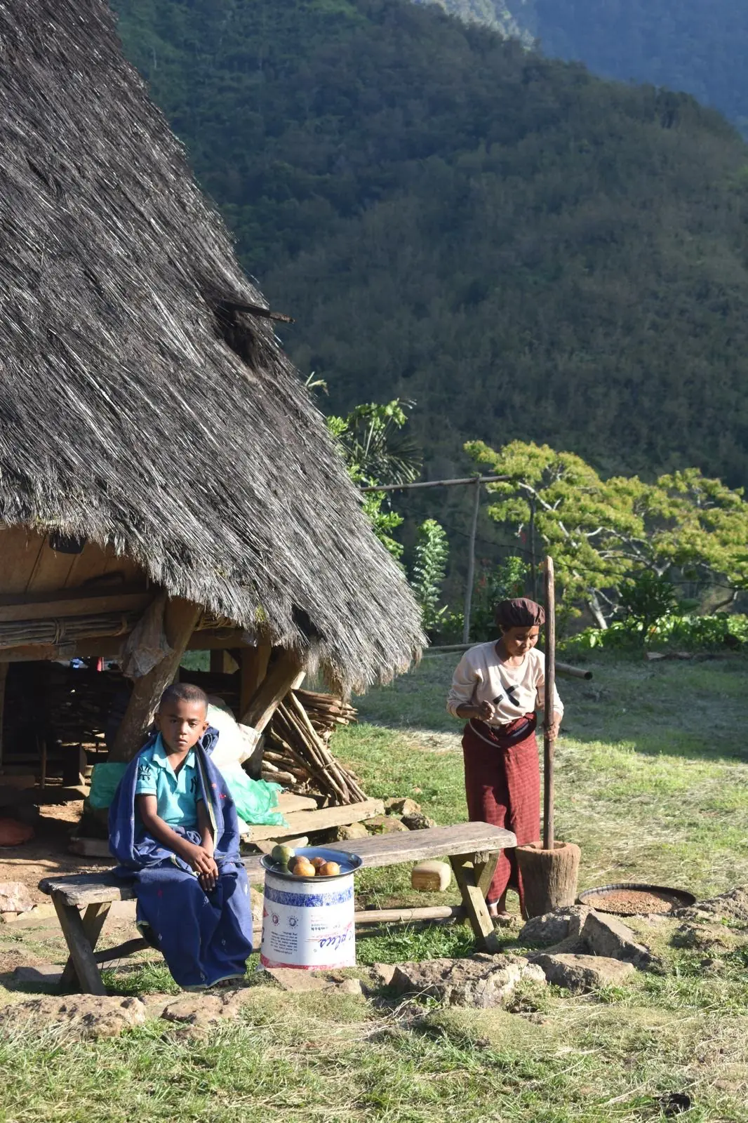 Vida cotidiana en Wae Rebo: una mujer muele café junto a una mbaru niang